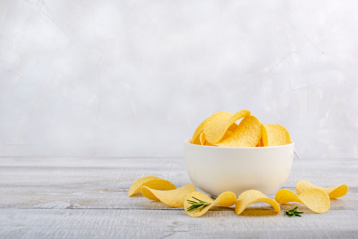 potato-chips-in-white-bowl-on-wooden-table-white-background