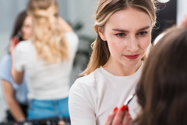 Free photo female visagiste putting makeup on client
